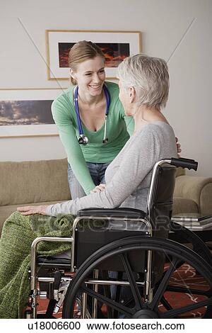 Stock Image - Young female nurse taking care of senior woman. Fotosearch
