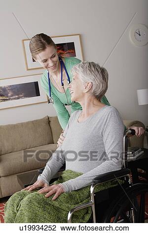 Stock Image - Young female nurse taking care of senior woman. Fotosearch