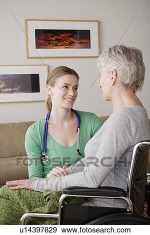 Stock Photo - Young female nurse taking care of senior woman. Fotosearch