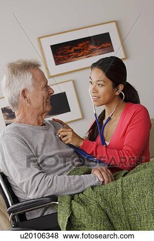 Stock Photo - Young female nurse taking care of senior man. Fotosearch