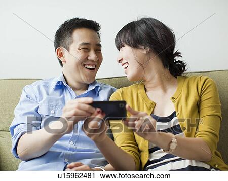 Young happy couple sitting on sofa View Large Photo Image Stock Image - Young happy couple sitting on sofa. Fotosearch