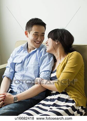 Young happy couple sitting on sofa View Large Photo Image Stock Photo - Young happy couple sitting on sofa. Fotosearch
