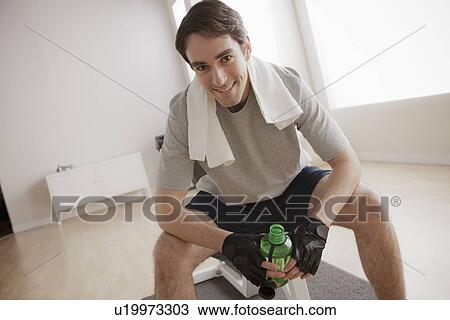 Stock Image - Young man exercising with dumbbell. Fotosearch
