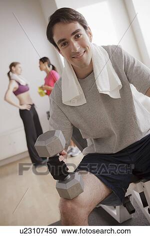 Stock Image - Young man exercising with dumbbell. Fotosearch