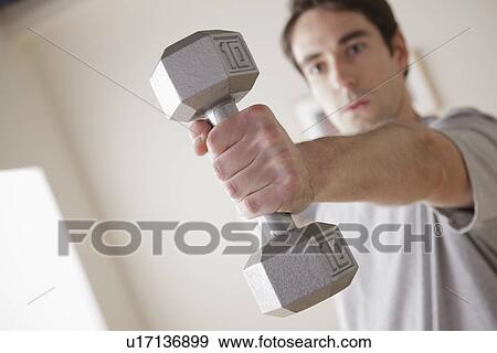 Young man exercising with dumbbell View Large Photo Image Stock Photo - Young man exercising with dumbbell. Fotosearch