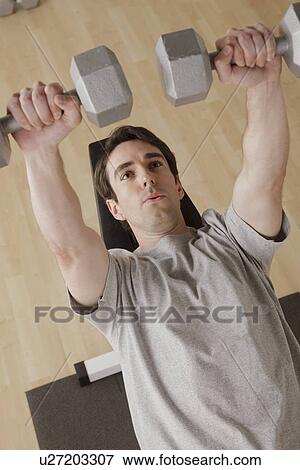 Stock Photo - Young man exercising with dumbbell. Fotosearch