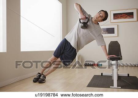 Picture - Young man exercising with weight. Fotosearch
