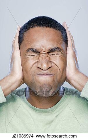 Young man with hands covering ears, studio shot View Large Photo Image Picture - Young man with hands covering ears, studio shot. Fotosearch