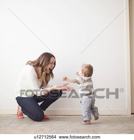 Young mother assisting baby boy (6-11 months) in first steps View Large Photo Image Picture - Young mother assisting baby boy (6-11 months) in first steps. Fotosearch