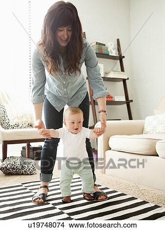 Young mother assisting baby boy (6-11 months) in his first steps View Large Photo Image Picture - Young mother assisting baby boy (6-11 months) in his first steps. Fotosearch