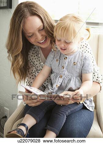 Stock Photo - Young mother reading to toddler girl (2-3). Fotosearch