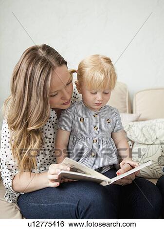 Stock Photograph - Young mother reading to toddler girl (2-3). Fotosearch