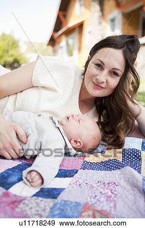 Stock Photo - Young mother with baby boy ( 2-5 months) lying on blanket. Fotosearch