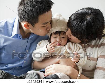 Stock Image - Young parents with baby girl (12-17 months). Fotosearch