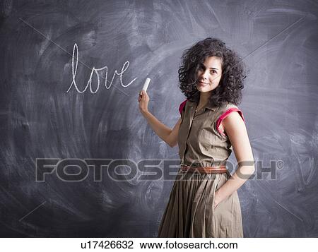 Young teacher posing against blackboard with word love written on it View Large Photo Image Stock Image - Young teacher posing against blackboard with word love written on it. Fotosearch