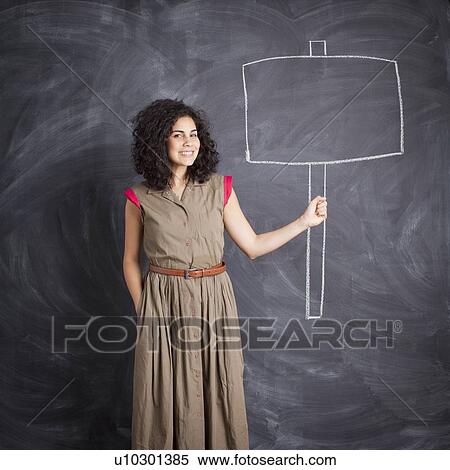 Young teacher posing against blackboard with blank banner written in chalk View Large Photo Image Stock Photography - Young teacher posing against blackboard with blank banner written in chalk. Fotosearch