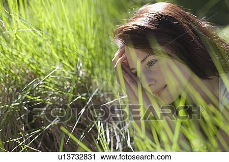 Young woman among green grass View Large Photo Image Stock Image - Young woman among green grass. Fotosearch