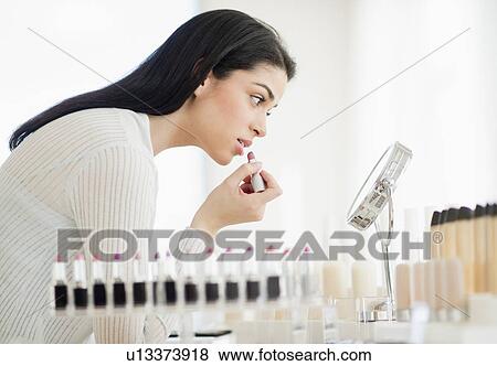 Young woman applying lipstick View Large Photo Image Stock Photo - Young woman applying lipstick. Fotosearch