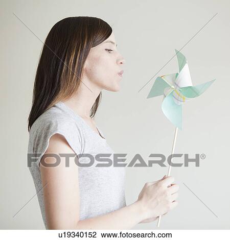 Young woman blowing at paper fan View Large Photo Image Stock Image - Young woman blowing at paper fan. Fotosearch