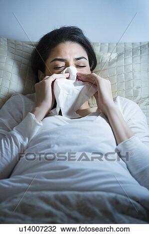 Young woman blowing nose in bed View Large Photo Image Stock Image - Young woman blowing nose in bed. Fotosearch