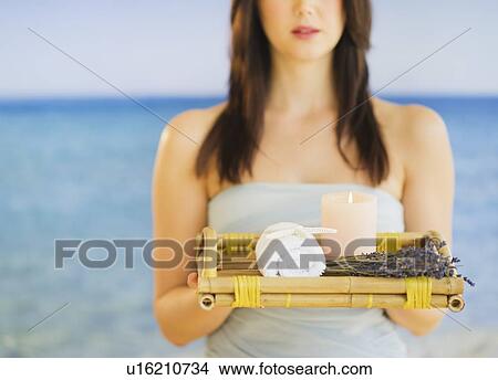 Young woman carrying tray with spa equipment, studio shot View Large Photo Image Picture - Young woman carrying tray with spa equipment, studio shot. Fotosearch