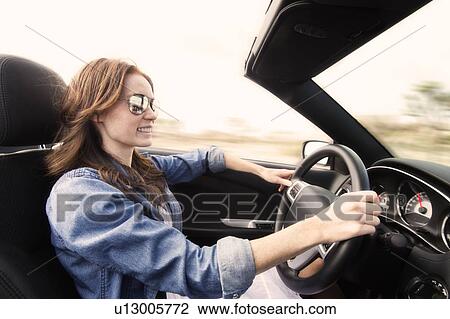 Stock Image - Young woman driving convertible. Fotosearch