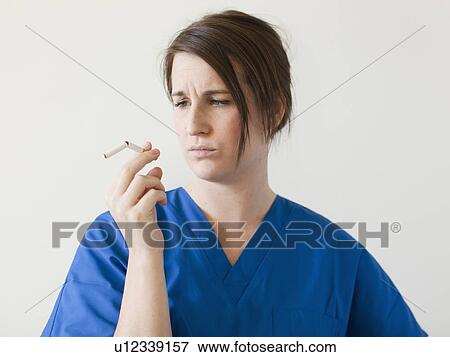 Young woman examining broke cigarette View Large Photo Image Stock Photo - Young woman examining broke cigarette. Fotosearch