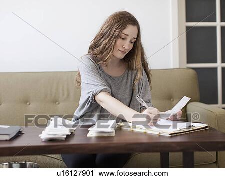 Young woman going though domestic paperwork View Large Photo Image Stock Image - Young woman going though domestic paperwork. Fotosearch