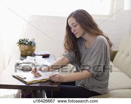 Stock Photo - Young woman going though domestic paperwork. Fotosearch
