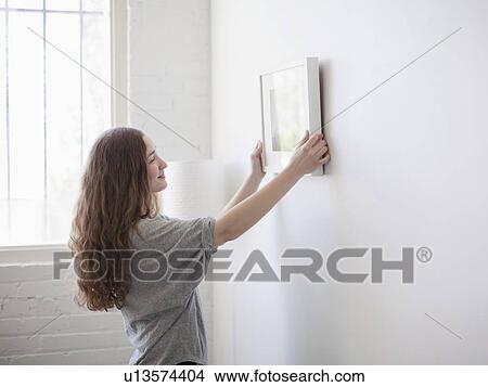 Young woman hanging picture on freshly painted wall View Large Photo Image Picture - Young woman hanging picture on freshly painted wall. Fotosearch