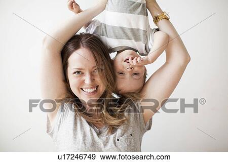 Young woman holding baby boy (6-11 months) upside-down View Large Photo Image Stock Photo - Young woman holding baby boy (6-11 months) upside-down. Fotosearch