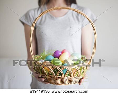 Stock Image - Young woman holding Easter egg basket. Fotosearch