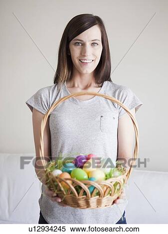 Stock Photography - Young woman holding Easter egg basket. Fotosearch