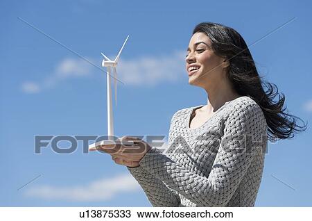Young woman holding toy wind turbine View Large Photo Image Stock Image - Young woman holding toy wind turbine. Fotosearch
