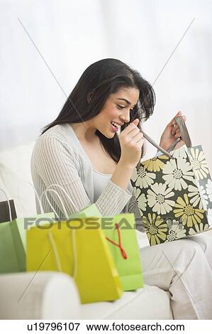 Stock Photo - Young woman looking into shopping bag. Fotosearch