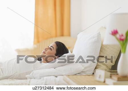 Young woman lying on bed View Large Photo Image Picture - Young woman lying on bed. Fotosearch