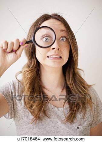 Young woman making a face while holding magnifying glass View Large Photo Image Picture - Young woman making a face while holding magnifying glass. Fotosearch
