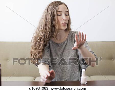 Stock Image - Young woman painting fingernails. Fotosearch