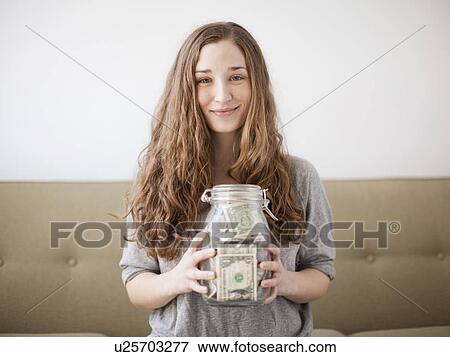 Stock Photo - Young woman presenting her savings jar . Fotosearch