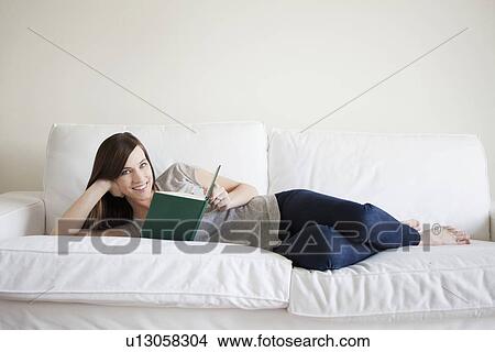 Young woman reclining on bed, reading book View Large Photo Image Picture - Young woman reclining on bed, reading book. Fotosearch