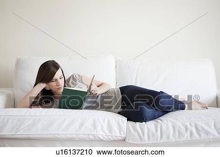 Young woman reclining on bed, reading book View Large Photo Image Stock Image - Young woman reclining on bed, reading book. Fotosearch