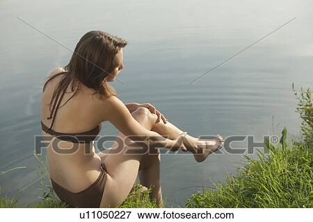 Stock Photo - Young woman relaxing on lakeside. Fotosearch