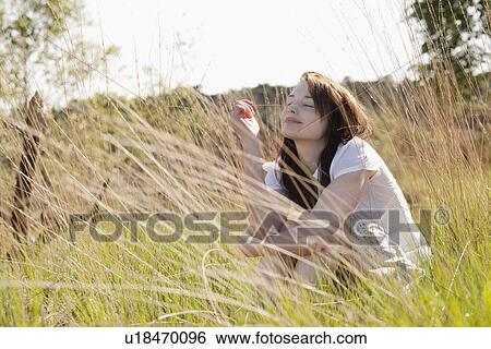 Stock Photograph - Young woman relaxing on meadow. Fotosearch