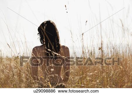 Stock Photograph - Young woman standing among cornfield. Fotosearch