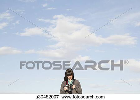 Stock Photo - Young woman taking photos. Fotosearch