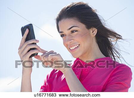 Stock Image - Young woman using PDA. Fotosearch