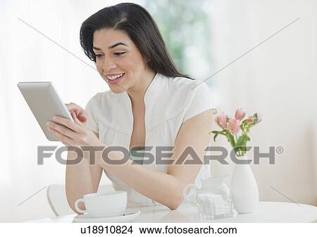 Picture - Young woman using tablet pc in restaurant. Fotosearch