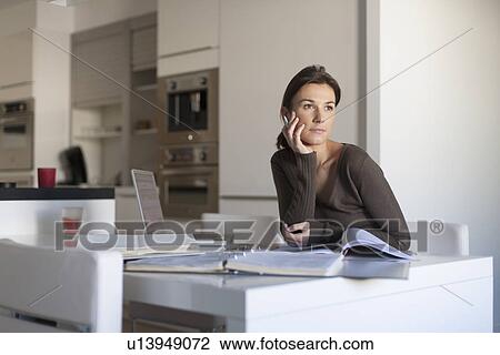 Stock Image - Young woman working from home. Fotosearch