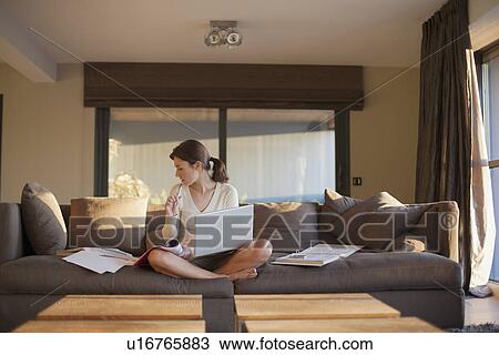 Stock Image - Young woman working from home. Fotosearch