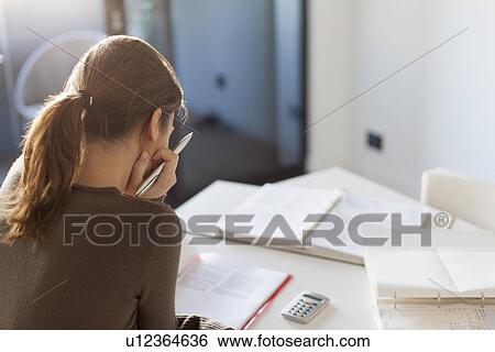 Stock Photograph - Young woman working from home. Fotosearch